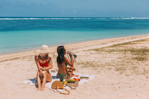 Two women sitting at a sunny beach